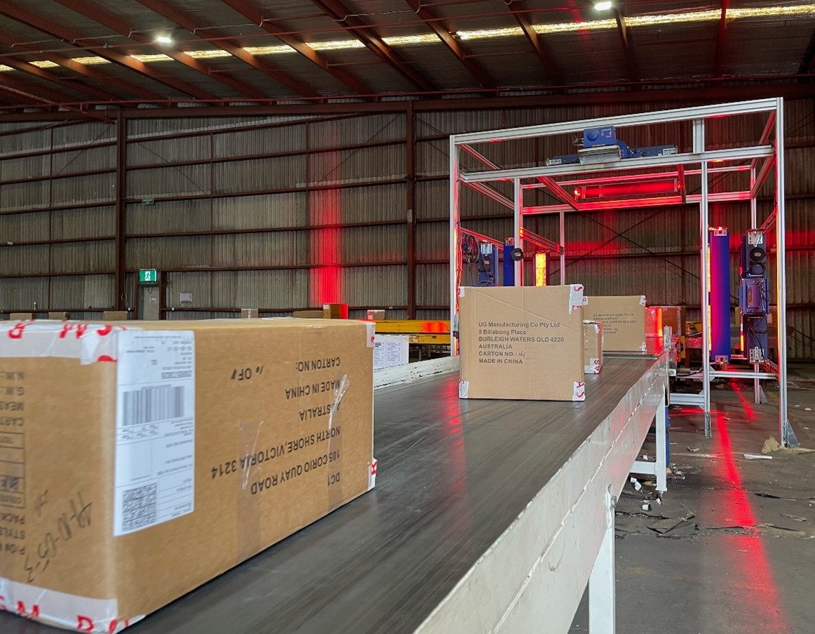 Boxes are carried along a conveyor belt to be laser scanned in an automated machine